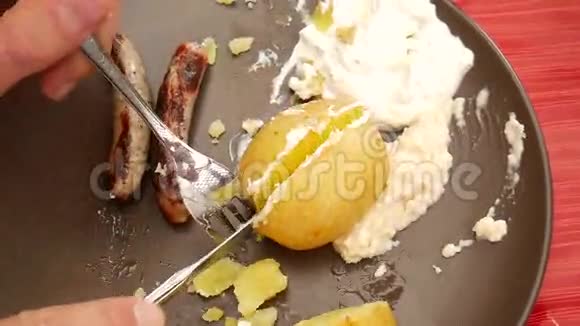 烤香肠和土豆用不锈钢刀叉在盘子里切视频的预览图