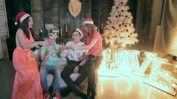 一群快乐的朋友靠近圣诞树喝着酒杯里的酒笑玩得开心视频的预览图