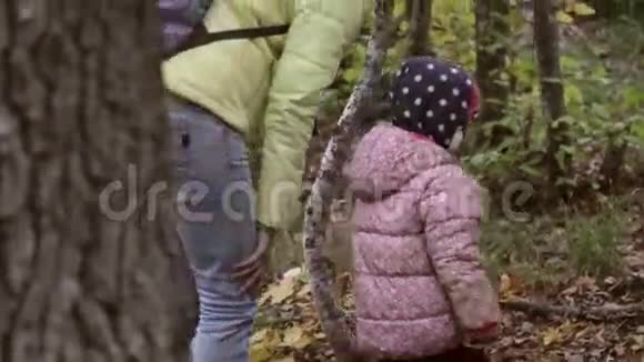 母亲和女儿穿着温暖的夹克走在秋天的森林里视频的预览图