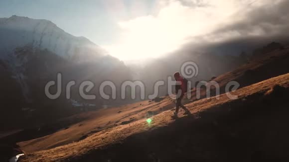 在美丽的日落中一个女孩在山的边缘行走的史诗般的画面视频的预览图