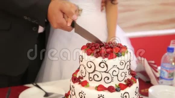新婚夫妇切了一块用新鲜浆果装饰的蛋糕视频的预览图