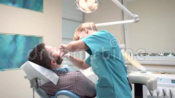 女性牙医检查男性病人的牙齿看相机视频的预览图