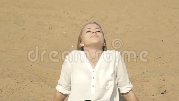 美丽的女孩坐在沙滩上微笑着视频的预览图
