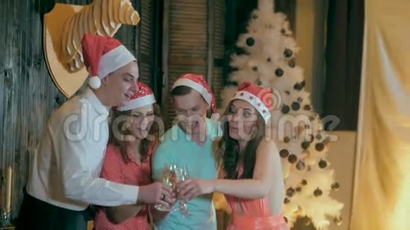 一群快乐的朋友靠近圣诞树喝着酒杯里的酒笑玩得开心视频的预览图