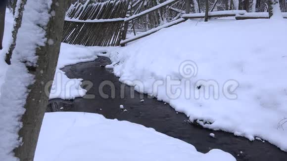 冬天的小溪流经雪域公园的木栅栏4K视频的预览图