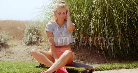运动美女坐在滑板上视频的预览图