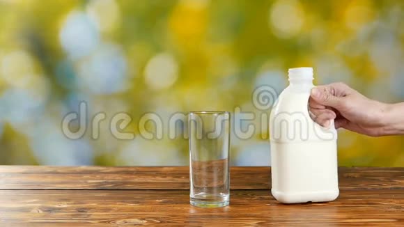 女人把新鲜牛奶倒入绿色背景的杯子里视频的预览图