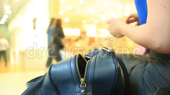 一个女人坐在购物中心的长凳上并不怀疑她的钱包狡猾的扒手偷了视频的预览图