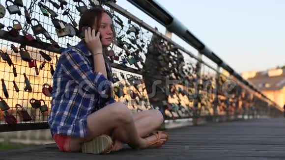 十几岁的女孩坐在恋人的桥上用手机聊天视频的预览图