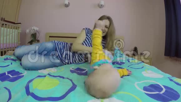 妈妈和4个月的宝宝上床玩得很开心快乐的母亲4K视频的预览图