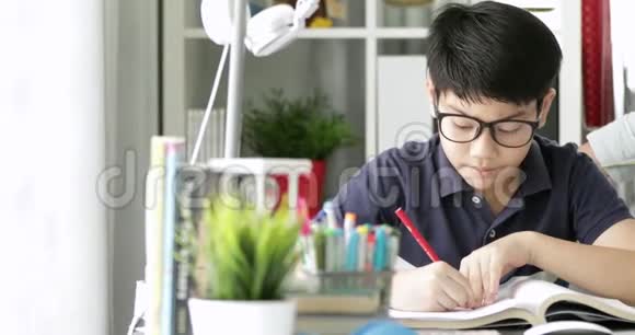 可爱的亚洲妈妈帮助你的儿子在家里做作业微笑着一起视频的预览图