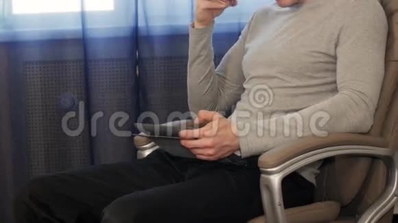 有平板电脑的人坐在椅子上喝茶视频的预览图