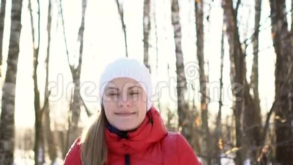 美丽的年轻女子在阳光明媚的冬季公园里玩雪玩得开心微笑慢动作视频的预览图
