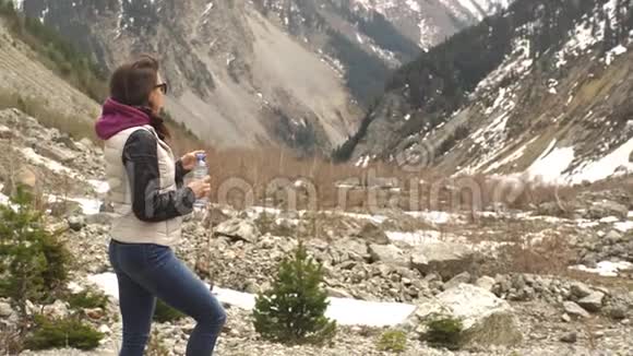 美丽的女性旅行者在美丽的山脉背景下喝水视频的预览图