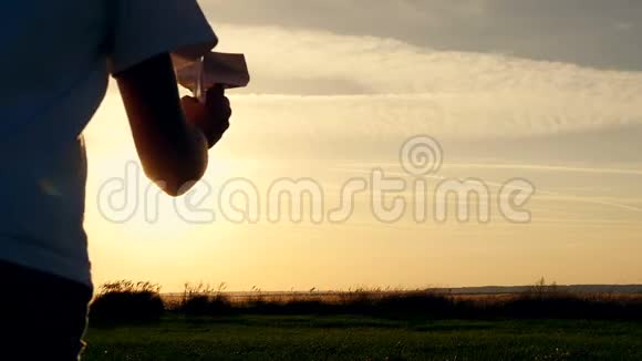 快乐的家伙在阳光下的田野里玩纸飞机日落时剪影视频的预览图