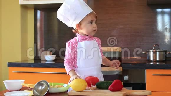 一个穿着厨师服的小娃娃在厨房里帮妈妈做饭视频的预览图