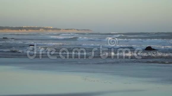 看到一个美丽的沙滩蓝色的波浪滚动到海岸一些岩石呈现视频的预览图