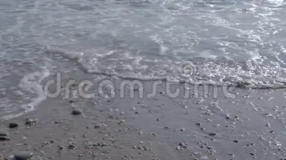 用白色泡沫波浪海滩上有沙子和鹅卵石视频的预览图