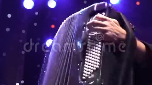 音乐家在舞台灯光阴影下手手风琴特写视频的预览图