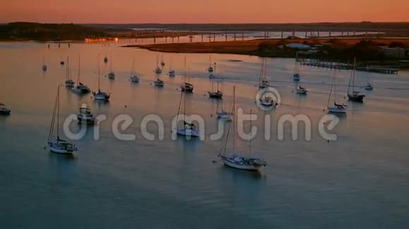 帆船在温暖的夕阳下停泊在城市海湾的河边视频的预览图