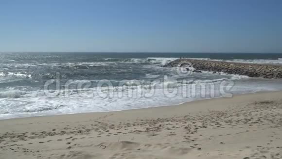 一个美丽的海洋沙滩与蓝色的波浪滚动到海岸一些岩石呈现视频的预览图