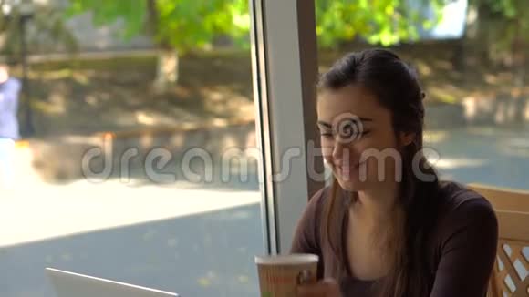 咖啡屋里有笔记本电脑的女孩在喝咖啡视频的预览图