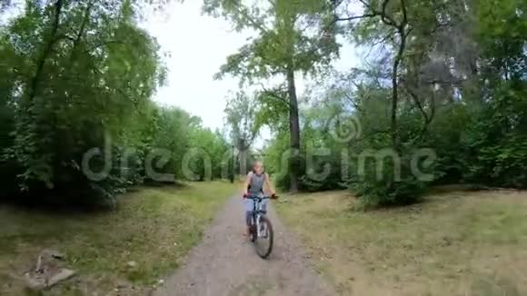 在公园里骑自行车在森林小径上骑自行车的女孩视频的预览图