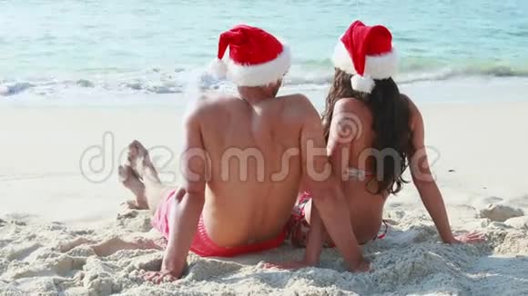夫妇带圣诞老人帽子看海洋的后景视频的预览图