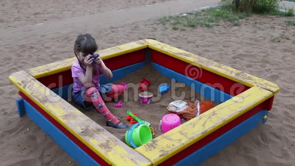 小女孩用玩具相机在沙箱里拍照视频的预览图