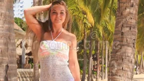 金发女孩带着花边特写的微笑来到海滩上的棕榈树视频的预览图