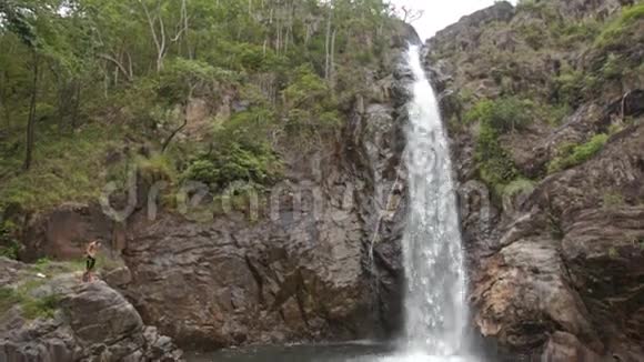 盖伊游向高瀑布泡沫飞溅的岩石视频的预览图
