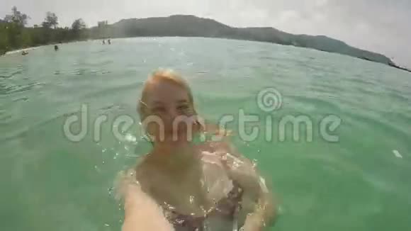 女人在海滩上拍自拍视频视频的预览图