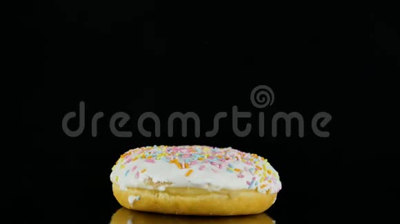 4K镜头的釉甜甜圈与洒以缓慢的速度旋转隔离在黑色视频的预览图