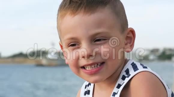 快乐的微笑着的小男孩穿着天空和大海背景的水手条纹衬衫视频的预览图