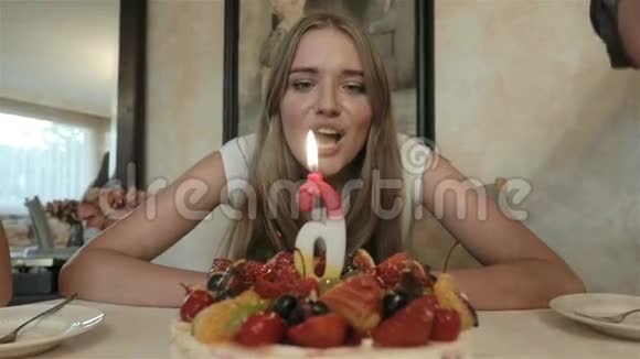 可爱的年轻女人坐在家里生日蛋糕前的肖像视频的预览图