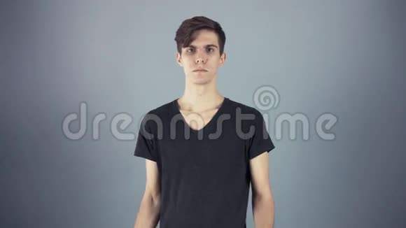 年轻男子身穿黑色衬衫手持绿色钥匙片海报灰色背景视频的预览图