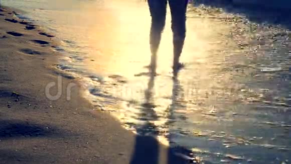 3女孩站在海边早晨她的脚被海浪卷起来视频的预览图