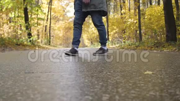 年轻的帅哥穿着夹克走在秋天的森林里在树林路上走视频的预览图