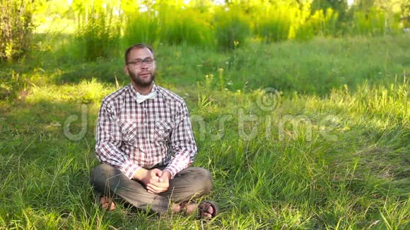戴眼镜的年轻人坐在草地上视频的预览图