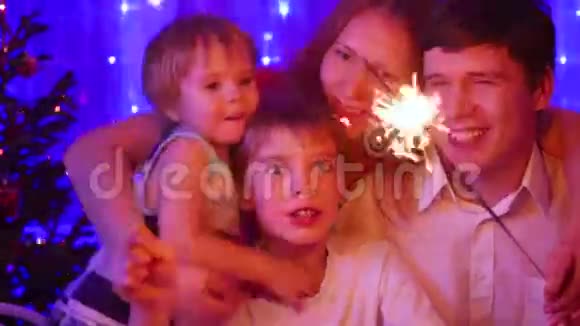 幸福的家庭在聚会上点燃了火花背景中圣诞杉木的灯光和花环视频的预览图