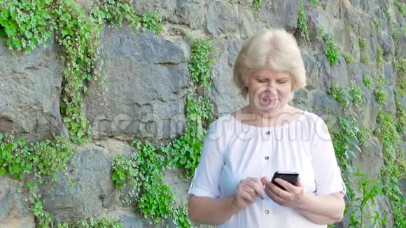 使用智能手机的老年妇女背景中野生石头的复古墙视频的预览图