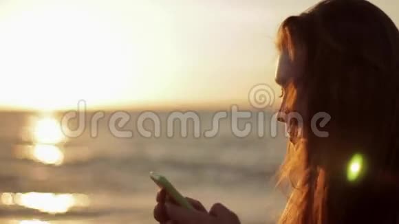 在海滩上使用智能手机的少女视频的预览图