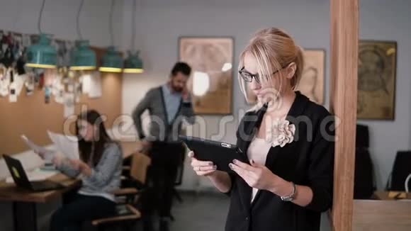 4k特写年轻漂亮的金发女商人在现代创业办公室使用触摸屏平板电脑视频的预览图