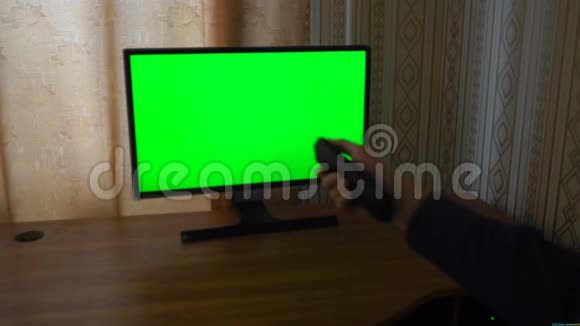男性手与电视远程切换频道的绿色屏幕电视观点视频的预览图