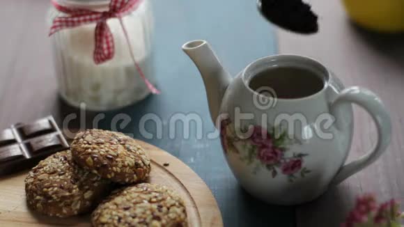 壶中红茶的配制用茶托将热茶倒入白色陶瓷杯中木制桌子饼干糖视频的预览图