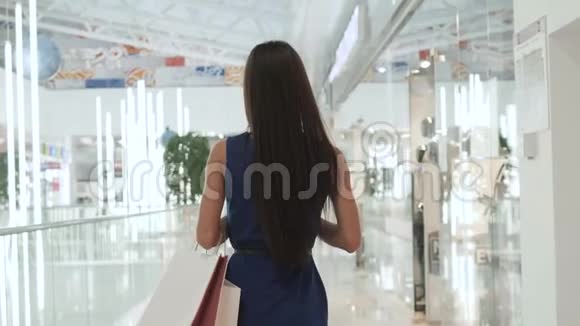 幸福美丽的女人拿着购物袋站在商店里漂亮的白种人女孩在大商场买包视频的预览图