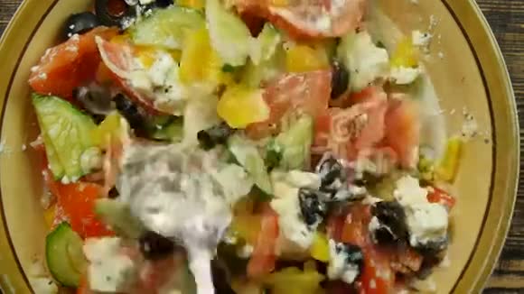 在厨房里搅拌新鲜蔬菜沙拉和奶酪沙拉蔬菜的混合特写视频的预览图