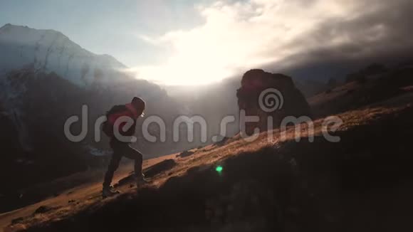 在美丽的日落中一个女孩在山的边缘行走作为一个剪影的史诗镜头的鸟瞰剪影视频的预览图