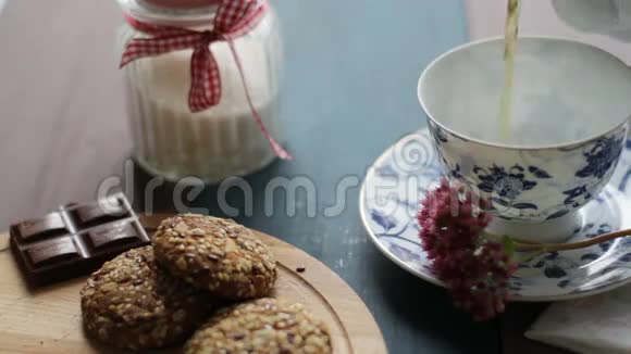 壶中红茶的配制用茶托将热茶倒入白色陶瓷杯中木制桌子饼干糖视频的预览图