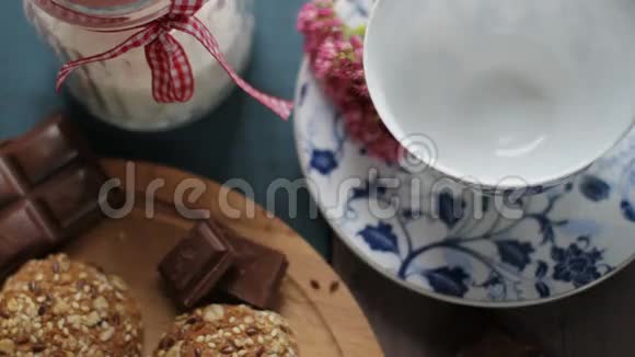 壶中红茶的配制用茶托将热茶倒入白色陶瓷杯中木制桌子饼干糖视频的预览图